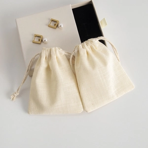 Detail of gold rectangle pearl earrings with cream drawer gift box and cotton pouches