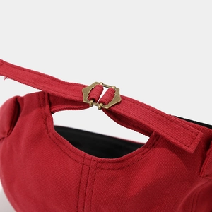 Close-up of red canvas hat showing metal strapback buckle and high-density cotton texture