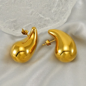 Close-up of golden teardrop earrings on grey satin with ice block decor detail