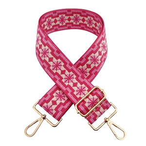 Detailed view of pink geometric jacquard bag strap with gold metal buckles