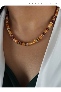 Nahaufnahme einer bunten Perlenkette an einem Model mit goldenen, roten und beigen Perlen