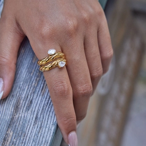 Close-up of gold double-twist ring with two pear-cut clear stones on model's finger