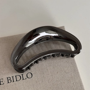 Macro detail of gun black metal hair claw clip with mirror finish and hollow crescent design