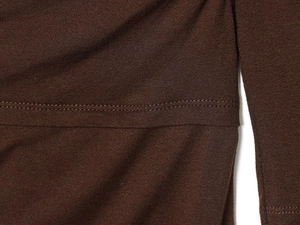 Gros plan détaillé du tissu en maille marron foncé avec couture double aiguille durable