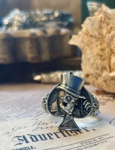 Détail d'une bague tête de mort rétro en argent avec motif pique sur fond rustique