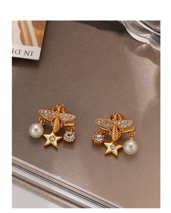 Detailed macro view of golden bee earring with sparkling crystals and a faux pearl drop