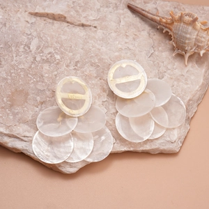 Detail of layered white shell discs and gold circular studs on natural stone background