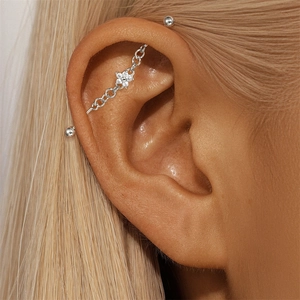 Detail shot of a s925 silver industrial barbell earring with star-moon chain and diamond flower
