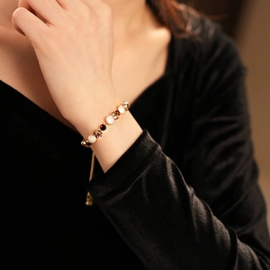 Bracelet ajustable doré avec perles blanches et ambrées porté sur le poignet