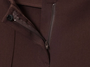 Detailed macro shot of dark brown twill fabric with metal zipper and resin button