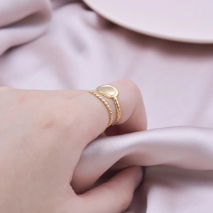 Close-up of golden stainless steel double-layered geometric ring on a silk background