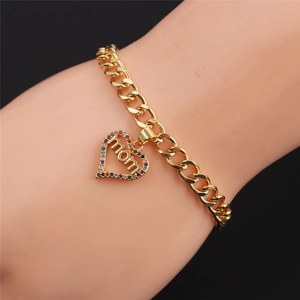 Detail of gold curb chain bracelet with colorful zircon heart MOM charm on wrist
