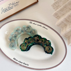 Elegant marble texture hair claws with floral patterns and rhinestones on a ceramic plate