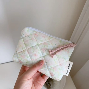 Quilted floral mini pouch held by hand showing compact size and zip detail