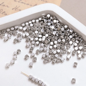 Macro detail of silver square spacer beads for DIY jewelry making on white tray