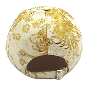 Detail of adjustable metal buckle and floral embroidery on a beige baseball cap