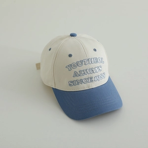 Close-up of color-block baseball cap featuring blue 3D embroidery on cream cotton fabric