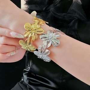 Gros plan de bracelets manchettes floraux en métal mat doré et argenté pour femmes