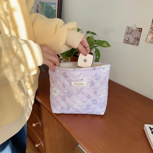 Close-up of lilac quilted floral makeup bag with cute animal patterns and woven label