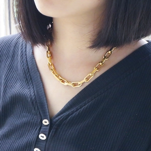 Close-up of golden Cuban link necklace with interlocked square-cut joints on a model