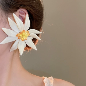 Close-up of a white resin floral earring with yellow center worn by a female model