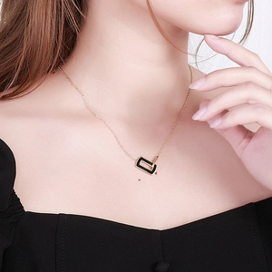 Close-up of model wearing a rose gold necklace with black enamel square lucky pendant