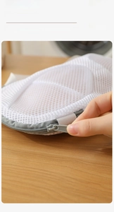 Detailed macro view showing the gray auto-lock zipper and elastic sleeve on white mesh laundry bag