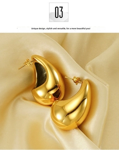 Detail of gold water drop earrings on silk fabric showing polished mirror finish