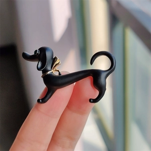 Close-up of black dachshund brooch with gold collar detail and matte finish texture