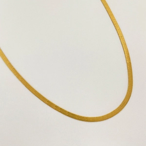 Macro detail of 3mm gold titanium steel flat snake chain necklace with smooth metallic finish