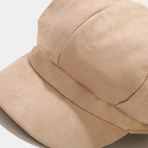 Detailed macro view of the khaki suede fabric texture and stitching on the newsboy cap
