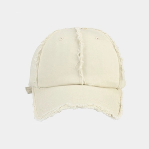 Detailed macro view of the distressed raw edges and twill cotton texture on a cream beige cap