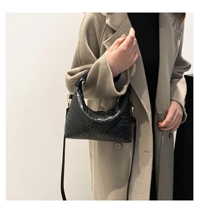 Close-up of black woven texture embossed shoulder bag with adjustable strap and handle