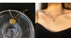 Detail of a gold heart pendant on a paperclip chain necklace with a starburst texture