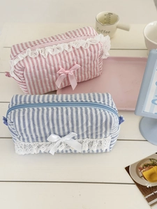 Détail de pochettes à rayures matelassées avec de la dentelle et un nœud en ruban