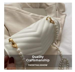 Detail of white V-quilted faux leather bag featuring elegant pearl and metal chain strap