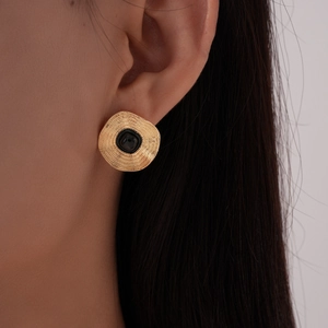 Gros plan sur les boucles d'oreilles vintage dorées avec émail noir sur le mannequin
