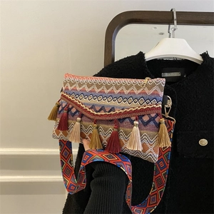 Detail of colorful woven bohemian bag with dense fringe tassels and wide geometric strap