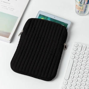 Close-up of black quilted tablet sleeve with vertical stitching and smooth metal zipper