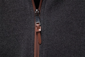 Detail of high-quality brown metal zipper with leather pull on dark grey hoodie fabric