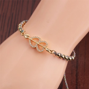 Detail of adjustable golden heart bracelet with colorful woven rope on a model's wrist
