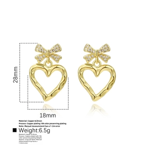 Dettaglio orecchini a cuore e fiocco placcati oro 18k con pietre di zircone lucenti