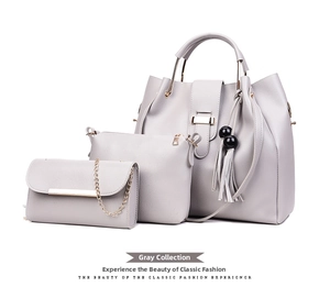Three-piece grey handbag set featuring tote, pouch, and chain wallet with tassel detail