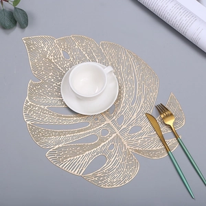 Gold hollowed monstera leaf placemat set with elegant tea cup and golden cutlery