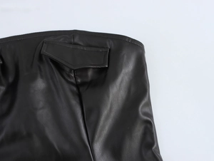 Detail shot of the faux leather texture and back flap pocket design on a black mini skirt