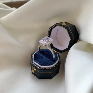Macro shot of rectangular cut diamond ring in a luxury navy blue velvet gift box