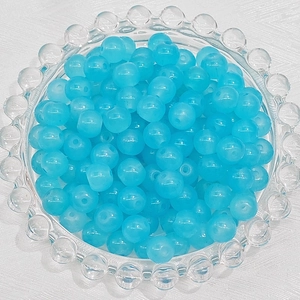 Macro shot of sky blue round translucent glass beads for DIY jewelry making in a glass tray