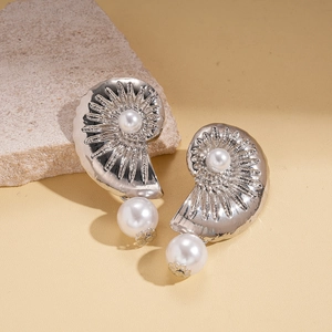 Silver shell-shaped earrings with white pearls displayed on a natural stone background