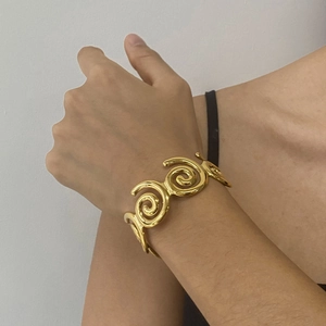 Macro shot of gold spiral open cuff bracelet with high-polish finish on model wrist