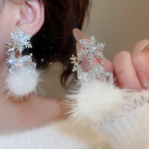 Detail of silver snowflake and deer earrings with white faux fur pom poms for Christmas